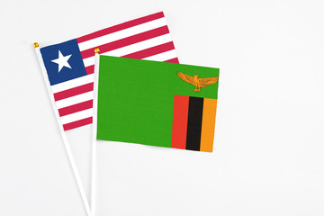 Zambia and Liberia stick flags on white background. High quality fabric, miniature national flag. Peaceful global concept.White floor for copy space.