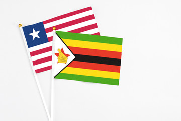 Zimbabwe and Liberia stick flags on white background. High quality fabric, miniature national flag. Peaceful global concept.White floor for copy space.