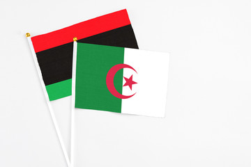 Algeria and Libya stick flags on white background. High quality fabric, miniature national flag. Peaceful global concept.White floor for copy space.