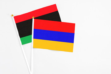 Armenia and Libya stick flags on white background. High quality fabric, miniature national flag. Peaceful global concept.White floor for copy space.