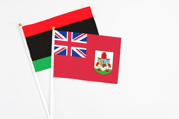 Bermuda and Libya stick flags on white background. High quality fabric, miniature national flag. Peaceful global concept.White floor for copy space.