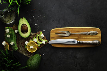 Avocado cooking recipes. Ripe green avocado on a wooden cutting board for serving.