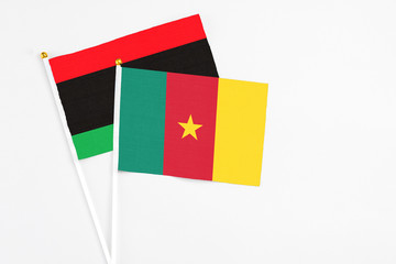 Cameroon and Libya stick flags on white background. High quality fabric, miniature national flag. Peaceful global concept.White floor for copy space.