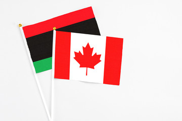 Canada and Libya stick flags on white background. High quality fabric, miniature national flag....