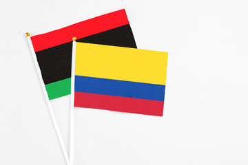 Colombia and Libya stick flags on white background. High quality fabric, miniature national flag. Peaceful global concept.White floor for copy space.