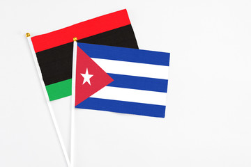 Cuba and Libya stick flags on white background. High quality fabric, miniature national flag. Peaceful global concept.White floor for copy space.