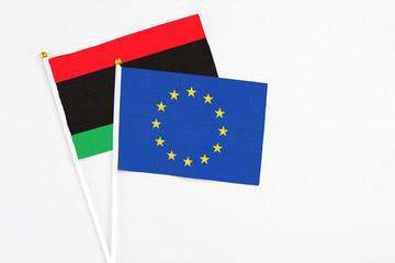 European Union and Libya stick flags on white background. High quality fabric, miniature national flag. Peaceful global concept.White floor for copy space.