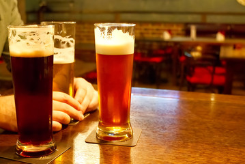 three glasses with beer on a table in a bar, filtered beer, dark beer and copper beer. Meeting with friends