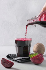 Pouring beetroot juice from bottle to glass. Close up. Vertical orientation.
