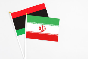 Iran and Libya stick flags on white background. High quality fabric, miniature national flag. Peaceful global concept.White floor for copy space.
