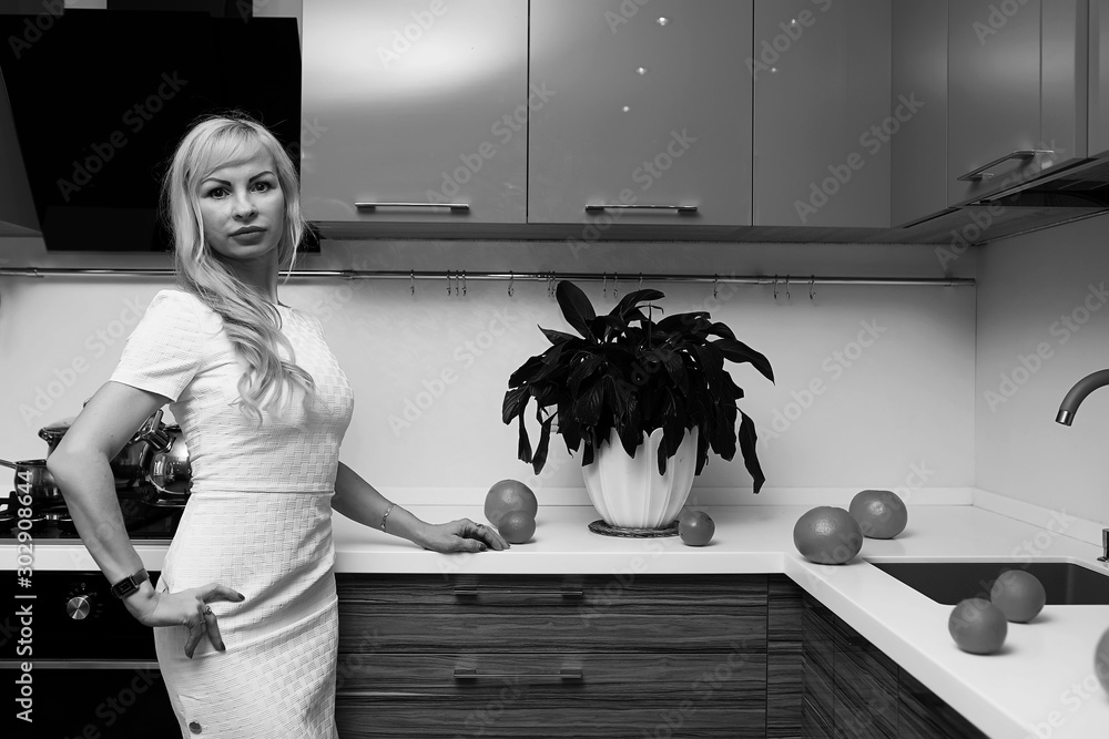 Wall mural black and white photo of blonde girl posing on camera in kitchen