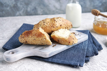 Naklejka premium A freshly baked crunchy homemade bread with butter, seeds on wooden board, bottle of milk. Healthy organic breakfast.