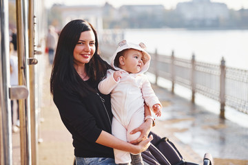 Mother with pram in casual clothes with her child is in the park