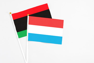 Luxembourg and Libya stick flags on white background. High quality fabric, miniature national flag. Peaceful global concept.White floor for copy space.