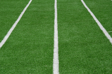 Obraz premium white line as running lane on the green grass