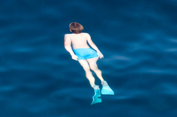 Fototapeta na wymiar A man swims in the blue water of the sea