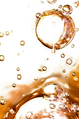 Bubbles of air on the smooth surface of golden water as an abstract background