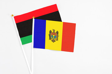 Moldova and Libya stick flags on white background. High quality fabric, miniature national flag. Peaceful global concept.White floor for copy space.