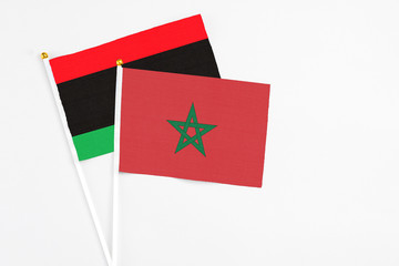Morocco and Libya stick flags on white background. High quality fabric, miniature national flag. Peaceful global concept.White floor for copy space.