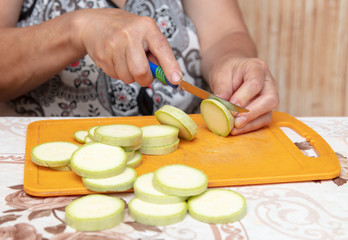 A woman cuts with a knife zucchini