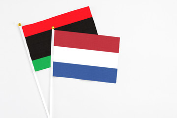 Netherlands and Libya stick flags on white background. High quality fabric, miniature national flag. Peaceful global concept.White floor for copy space.