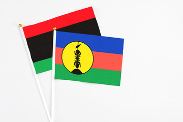 New Caledonia and Libya stick flags on white background. High quality fabric, miniature national...