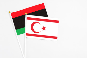 Northern Cyprus and Libya stick flags on white background. High quality fabric, miniature national flag. Peaceful global concept.White floor for copy space.