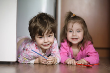 Naklejka premium Children boy and girl crawling on the floor. The children are smiling and lying on the floor. Children are playing at home.