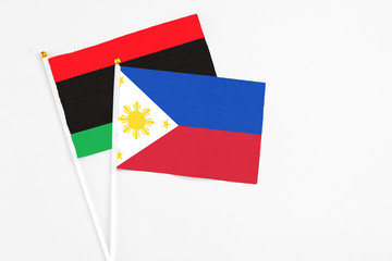 Philippines and Libya stick flags on white background. High quality fabric, miniature national flag. Peaceful global concept.White floor for copy space.