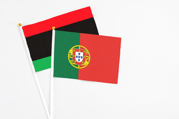Portugal and Libya stick flags on white background. High quality fabric, miniature national flag. Peaceful global concept.White floor for copy space.