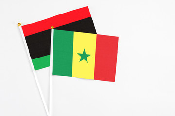 Senegal and Libya stick flags on white background. High quality fabric, miniature national flag. Peaceful global concept.White floor for copy space.