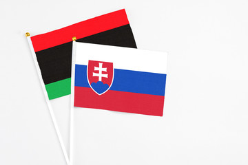 Slovakia and Libya stick flags on white background. High quality fabric, miniature national flag. Peaceful global concept.White floor for copy space.