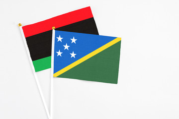 Solomon Islands and Libya stick flags on white background. High quality fabric, miniature national flag. Peaceful global concept.White floor for copy space.