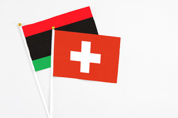 Switzerland and Libya stick flags on white background. High quality fabric, miniature national...