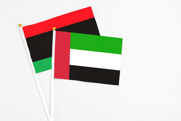 United Arab Emirates and Libya stick flags on white background. High quality fabric, miniature national flag. Peaceful global concept.White floor for copy space.