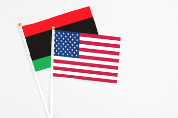 United States and Libya stick flags on white background. High quality fabric, miniature national flag. Peaceful global concept.White floor for copy space.