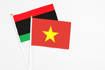 Vietnam and Libya stick flags on white background. High quality fabric, miniature national flag. Peaceful global concept.White floor for copy space.
