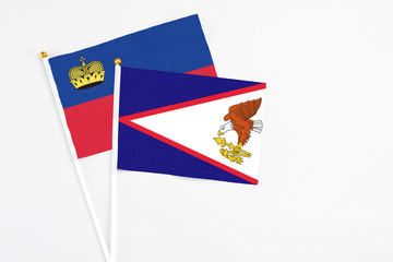 American Samoa and Liechtenstein stick flags on white background. High quality fabric, miniature national flag. Peaceful global concept.White floor for copy space.