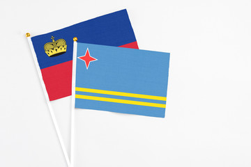 Aruba and Liechtenstein stick flags on white background. High quality fabric, miniature national flag. Peaceful global concept.White floor for copy space.