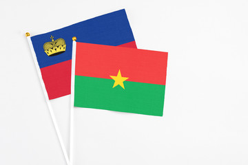 Burkina Faso and Liechtenstein stick flags on white background. High quality fabric, miniature national flag. Peaceful global concept.White floor for copy space.