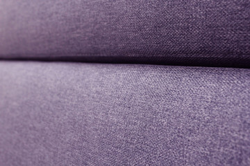 A fragment of the upholstery of the sofa. Selective focus. Purple upholstery fabric.