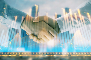 Double exposure of financial graph on cityscape background with two businessman handshake. Concept of stock market deal