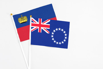 Fototapeta premium Cook Islands and Liechtenstein stick flags on white background. High quality fabric, miniature national flag. Peaceful global concept.White floor for copy space.