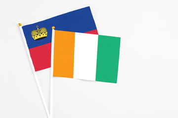 Cote D'Ivoire and Liechtenstein stick flags on white background. High quality fabric, miniature national flag. Peaceful global concept.White floor for copy space.