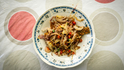 Fermented fried freshwater bream fish with fried onion or ikan pekasam in a plate on table.