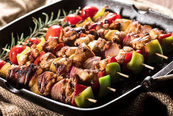 Grilled chicken skewers with spices and vegetables in a pan