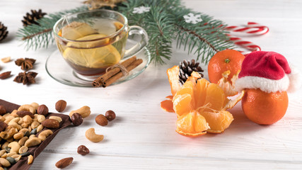 Fototapeta na wymiar Christmas tea, nuts and tangerines on a white wooden background