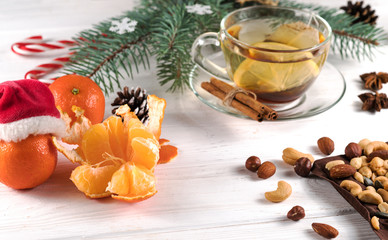 Christmas tea, nuts and tangerines on a white wooden background