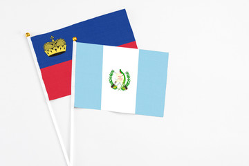 Guatemala and Liechtenstein stick flags on white background. High quality fabric, miniature national flag. Peaceful global concept.White floor for copy space.