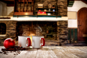 Christmas mugs with a hot drink. Steam smoke and Christmas decoration. Blurry background of a rustic fireplace with flame. American rifles on a stand. Place for your christmas gifts.Dark mood shadows.